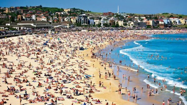 A crowded beach with people sunbathing and swimming, surrounded by buildings. - Art-Deco Gem in Midlothian, Opposite Beach (Bellevue Hill)