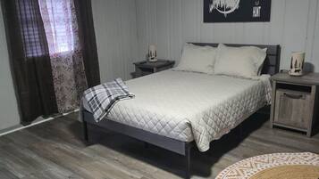 A bedroom with a bed, two bedside tables, a wall clock, and a rug.