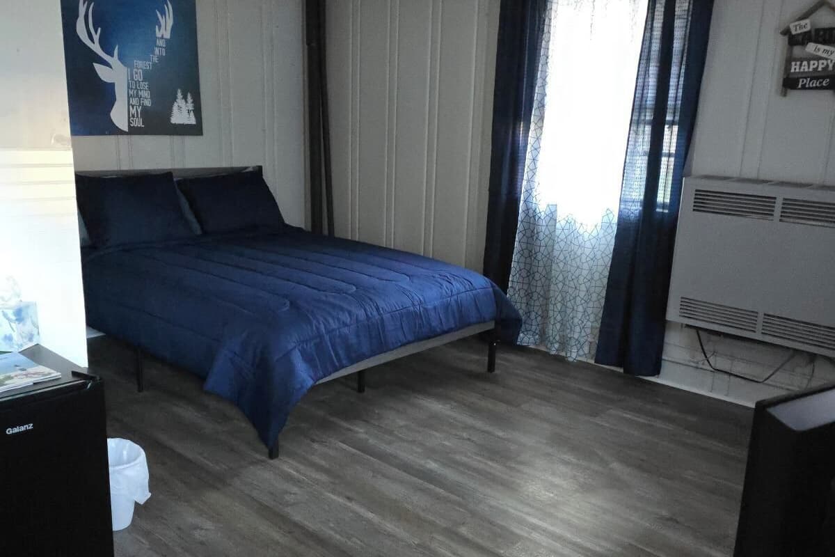 A bedroom with a bed, a desk, and a television.