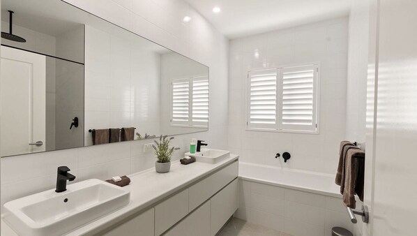 A modern bathroom with two sinks, a large mirror, and a bathtub. - Kwilena, Brand new Holiday home in an amazing location. (Exmouth)