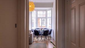 En spiseplads med et rundt bord, stole og en hængende lampe.