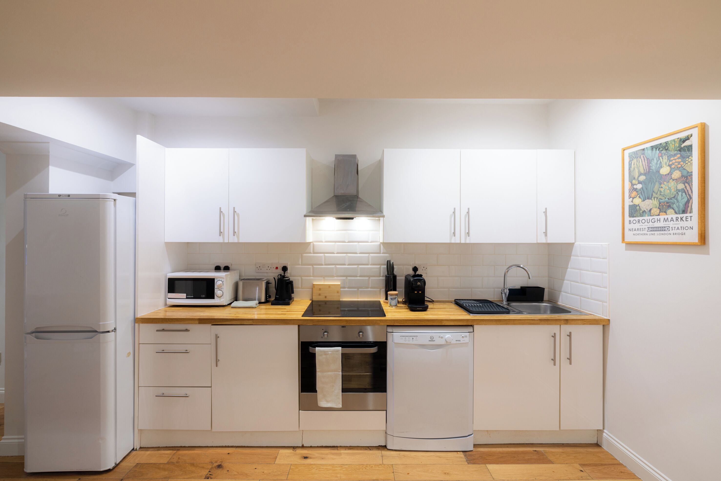 A compact kitchen with white cabinets, a microwave, a toaster, a sink, and a dishwasher.