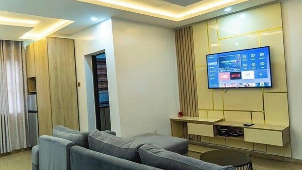 Una sala de estar moderna con una televisión de pantalla plana montada en la pared, un sofá gris y una pequeña mesa de centro.