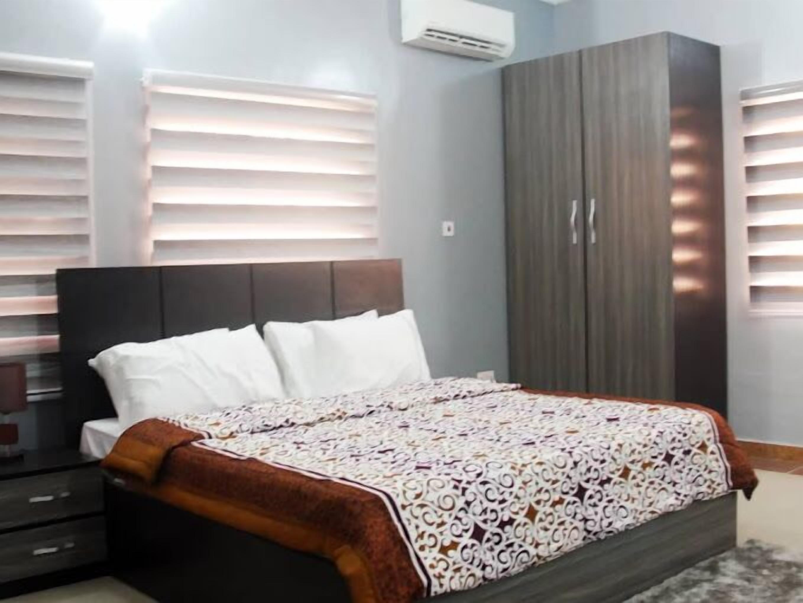 Un dormitorio con cama, armario y ventana con persianas.