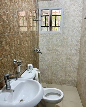 Un baño con lavamanos, inodoro y ducha.