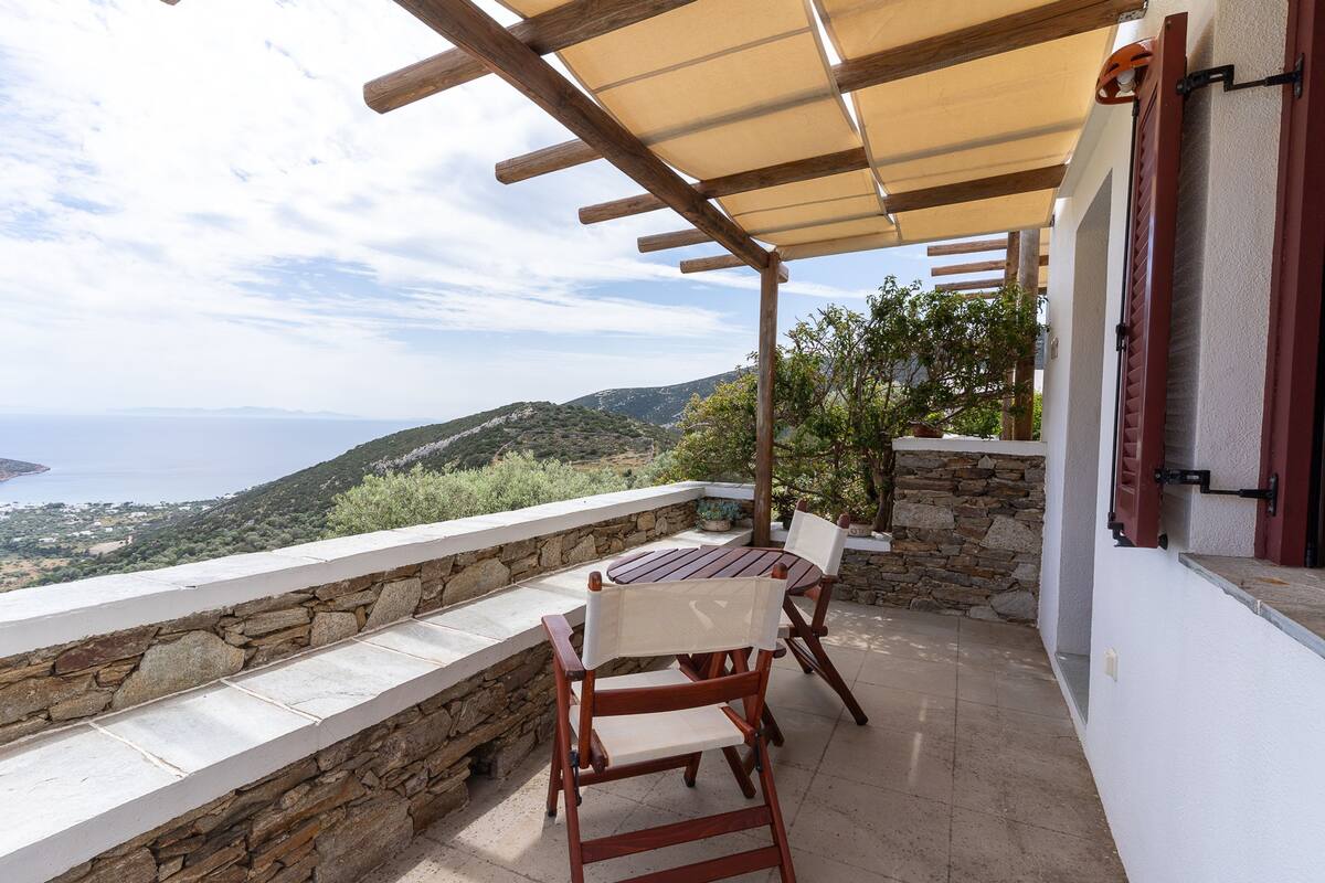 A terrace with a table and chairs, stone walls, and a view of the sea.