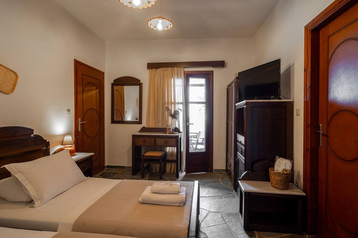 A hotel room with a bed, a desk, a television, and a wardrobe.