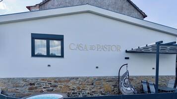 Un edificio con cimientos de piedra y sección superior blanca. Se lee “CASA DO PASTOR” en la pared.