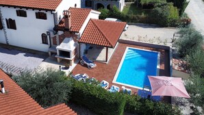 En villa med en swimmingpool, utomhusmöbler och en trädgård.