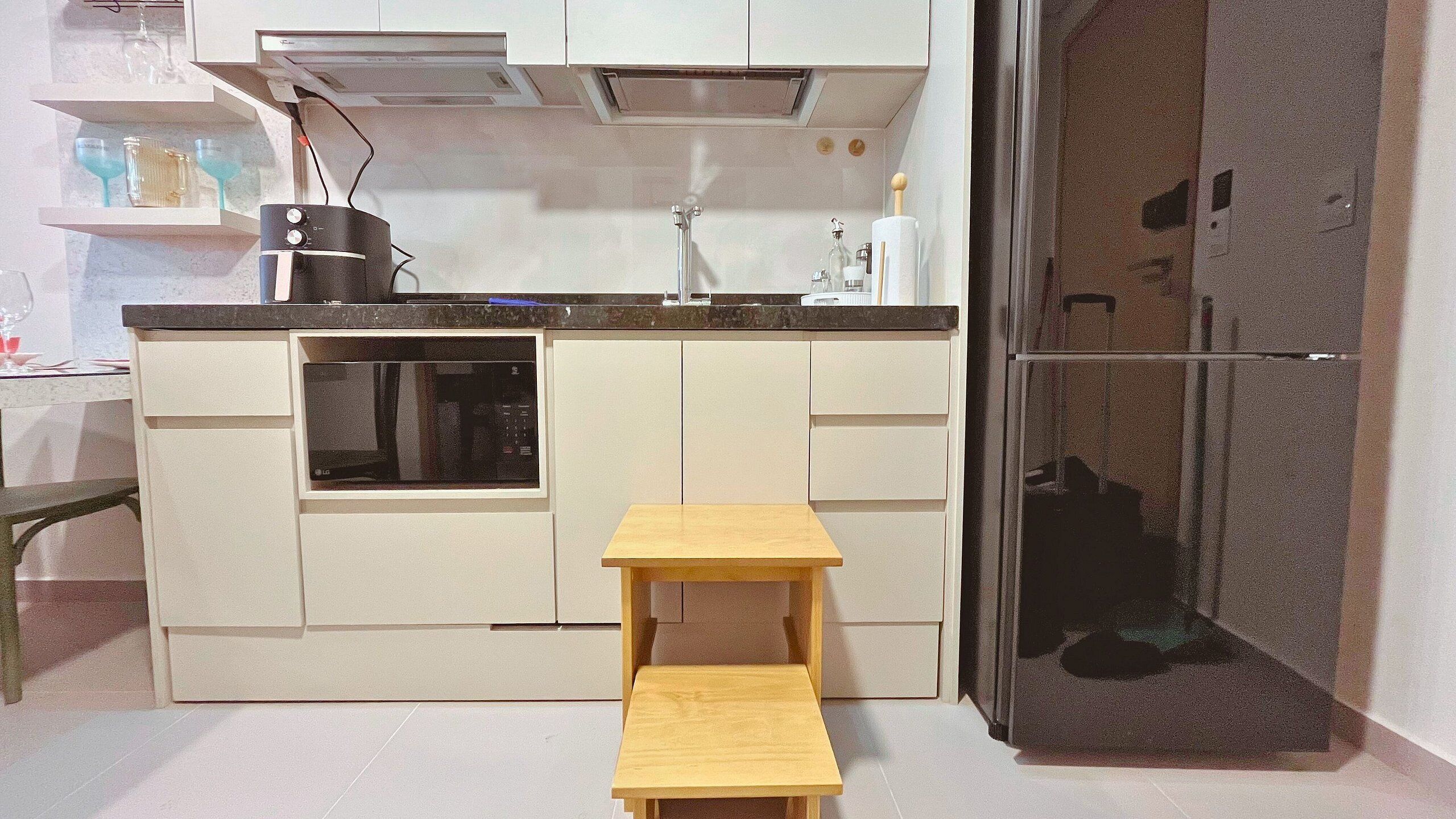 A compact kitchen with a microwave, a small wooden table, and a refrigerator.