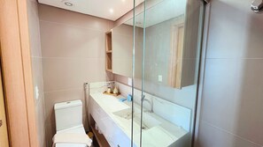 A modern bathroom with a glass shower enclosure, a white toilet, and a marble sink. - Flat Oceânica Seaside - By Almare (João Pessoa)