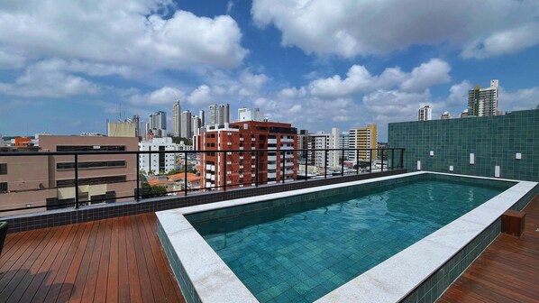 A rooftop pool with a city skyline in the background. - Flat Oceânica Seaside - By Almare (João Pessoa)