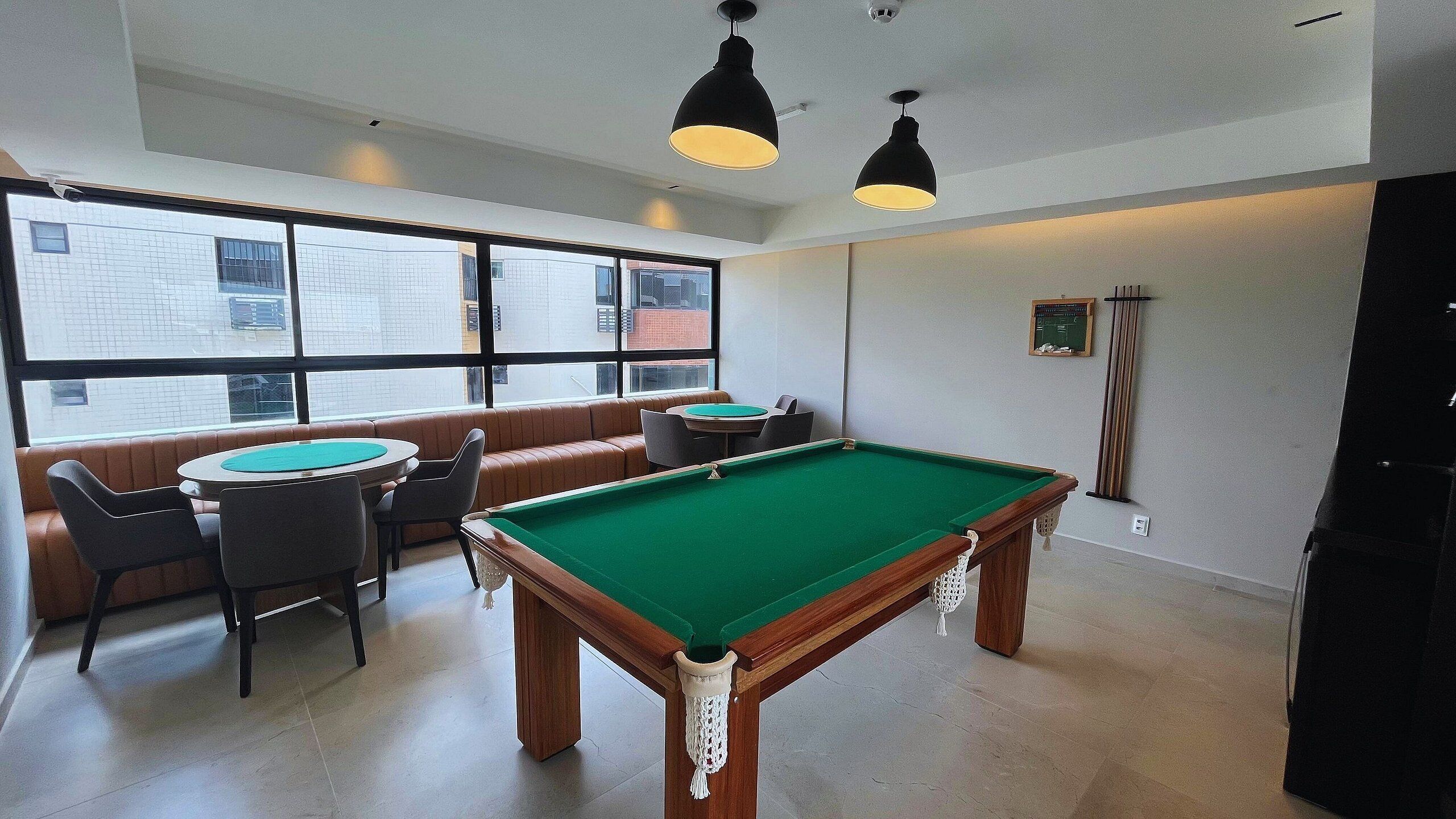 A billiards room with a pool table, seating area, and large windows.