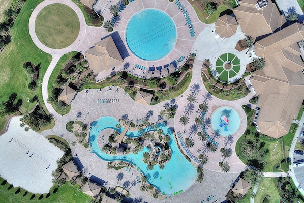 Vista aérea de un resort con una piscina central, varias piscinas más pequeñas y zonas ajardinadas con palmeras y senderos.