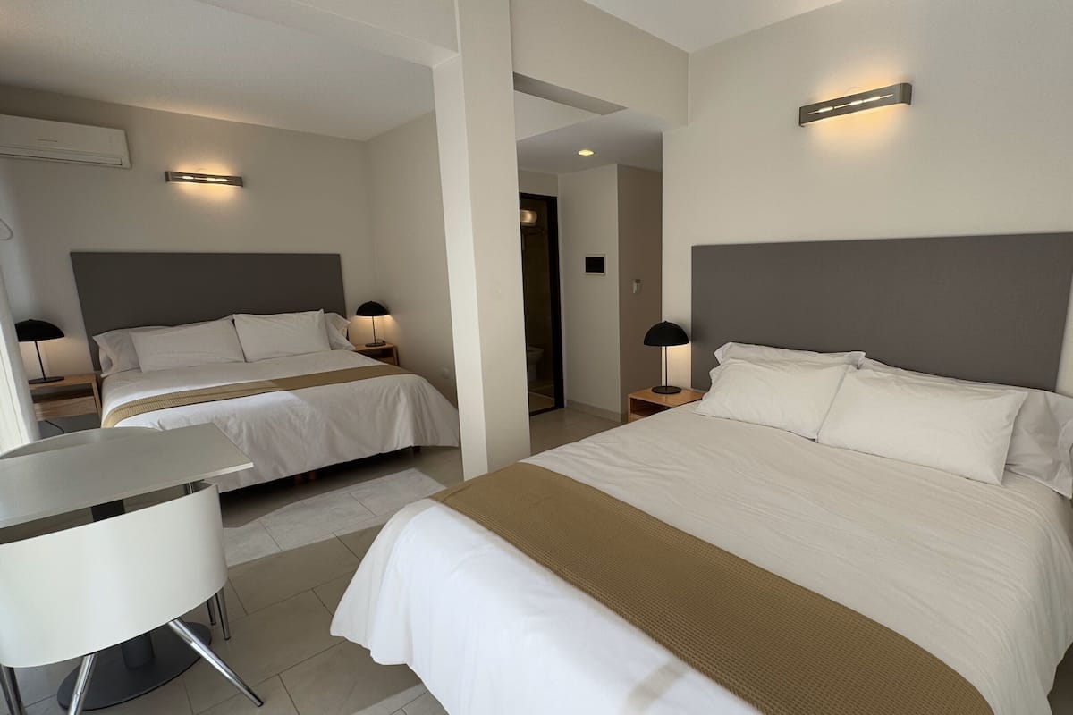 A hotel room with two beds, a desk, and a chair.