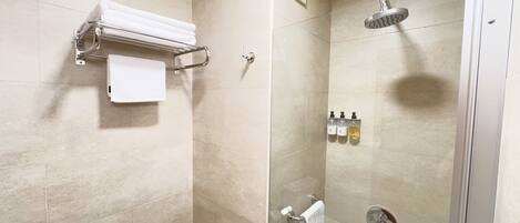 A modern shower with a handheld showerhead, a glass-enclosed shower stall, and a towel rack with folded towels.