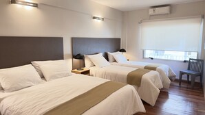 A hotel room with two beds, a window with a view, a chair, and a wall-mounted air conditioner. - Urbe Hotel (Buenos Aires)