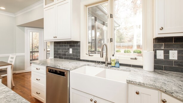 A modern kitchen with white cabinetry, a double sink, and a dishwasher.
