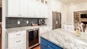 A modern kitchen with white cabinets, a granite countertop, and a stainless steel refrigerator.
