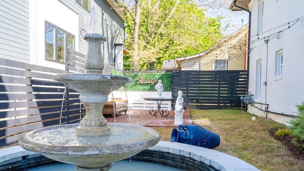 A fountain in a backyard with a wooden fence, a bench, and a statue. - Beautiful Historic DT Raleigh (Raleigh)