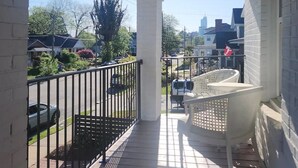 A covered porch with a railing, a hanging light fixture, and a view of the neighborhood. - Beautiful Historic DT Raleigh (Raleigh)