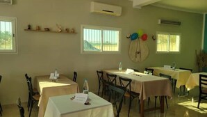 Un espace repas avec des tables dressées pour les clients, des appareils de climatisation et une vue sur l’extérieur.
