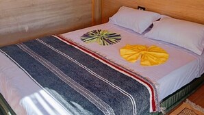 Un lit avec une couverture à rayures, un coussin décoratif rond et un coussin en forme de nœud.