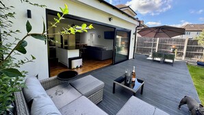 Una casa moderna con un amplio patio, una zona de comedor y una cocina visible a través de una puerta corrediza abierta.