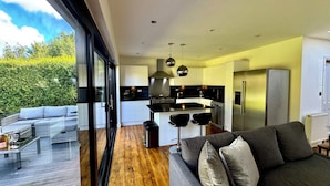 Una cocina moderna con una isla central, electrodomésticos de acero inoxidable y un comedor con sofá y sillas.