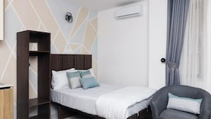 A compact bedroom with a bed, a chair, a wardrobe, and a wall-mounted air conditioning unit.