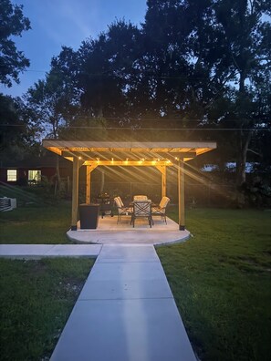 A covered patio with outdoor furniture and string lights.