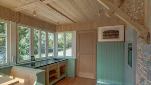 A kitchen with wooden beams, a large window, and a stone wall. - New top-equipped vacation apartment - 20m to the lake in historic monastery fiefdom (Tegernsee)