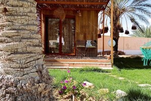 Eine Holzhütte mit Glastür, einer kleinen Veranda und einer Palme.