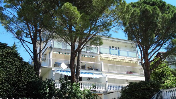 Un immeuble de deux étages doté de balcons, avec un arbre devant.
