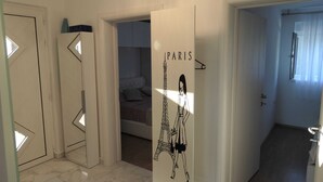Un intérieur moderne au design minimaliste, comprenant un lit, une armoire et une porte ornée d’une illustration sur le thème de Paris.
