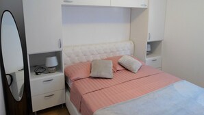 Une chambre à coucher comprenant un lit, des tables de chevet, un miroir et des placards intégrés.