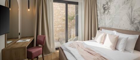 A hotel room with a bed, a desk, a chair, and a large window with curtains.