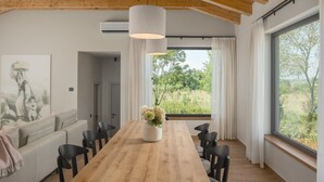 A modern dining area with a wooden table, black chairs, and a vase of flowers. - Luxury Villa in Tar With View (Tar-Vabriga)