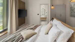 A modern bedroom with a large bed, a TV mounted on the wall, a wardrobe, and a bathroom visible through an open door. - Luxury Villa in Tar With View (Tar-Vabriga)