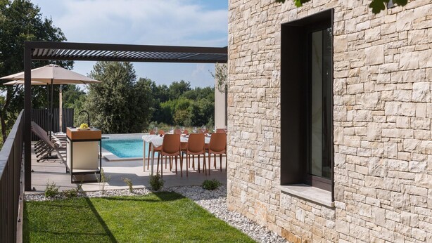 A stone building with a pool, outdoor seating, and a pergola.