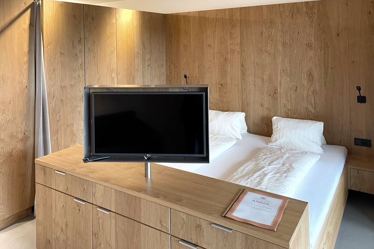 A bedroom with a bed, a TV on a wooden dresser, and a sign on the dresser.