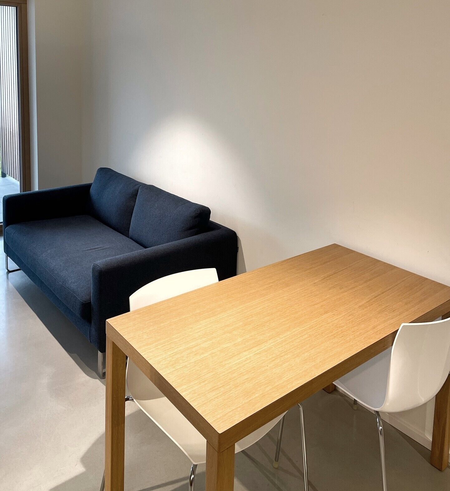 A modern room with a dark grey sofa, a wooden table, and a white chair.