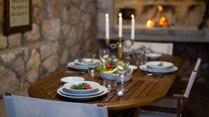 A dining table set with plates, glasses, and cutlery, with a stone wall and a fireplace in the background. - Tranquil Getaway Polje Villa With Pool (Dobrinj)