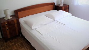 A neatly made bed with white linens, a wooden headboard, and two bedside tables with lamps. - Airy Crikvenica Apartment With Terrace Close to Beach (Crikvenica)