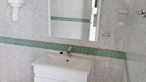 Une salle de bain avec un lavabo blanc, un miroir au-dessus et un mur recouvert de carreaux décoratifs.