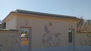 Un bâtiment à la façade beige, doté d’un toit végétalisé et orné de motifs décoratifs sur les murs, représentant des oiseaux et des motifs floraux.