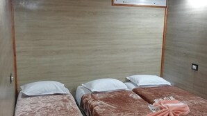 Une chambre avec deux lits, chacun recouvert d’une couverture marron et agrémenté d’oreillers blancs.