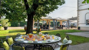An outdoor dining area with round tables, chairs, and umbrellas. - Villa Laguna 10, Emma VIllas (Faenza)