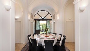 A dining area with a round table set for six, surrounded by wicker chairs, white tablecloths, and a vase of flowers. - Villa Laguna 10, Emma VIllas (Faenza)
