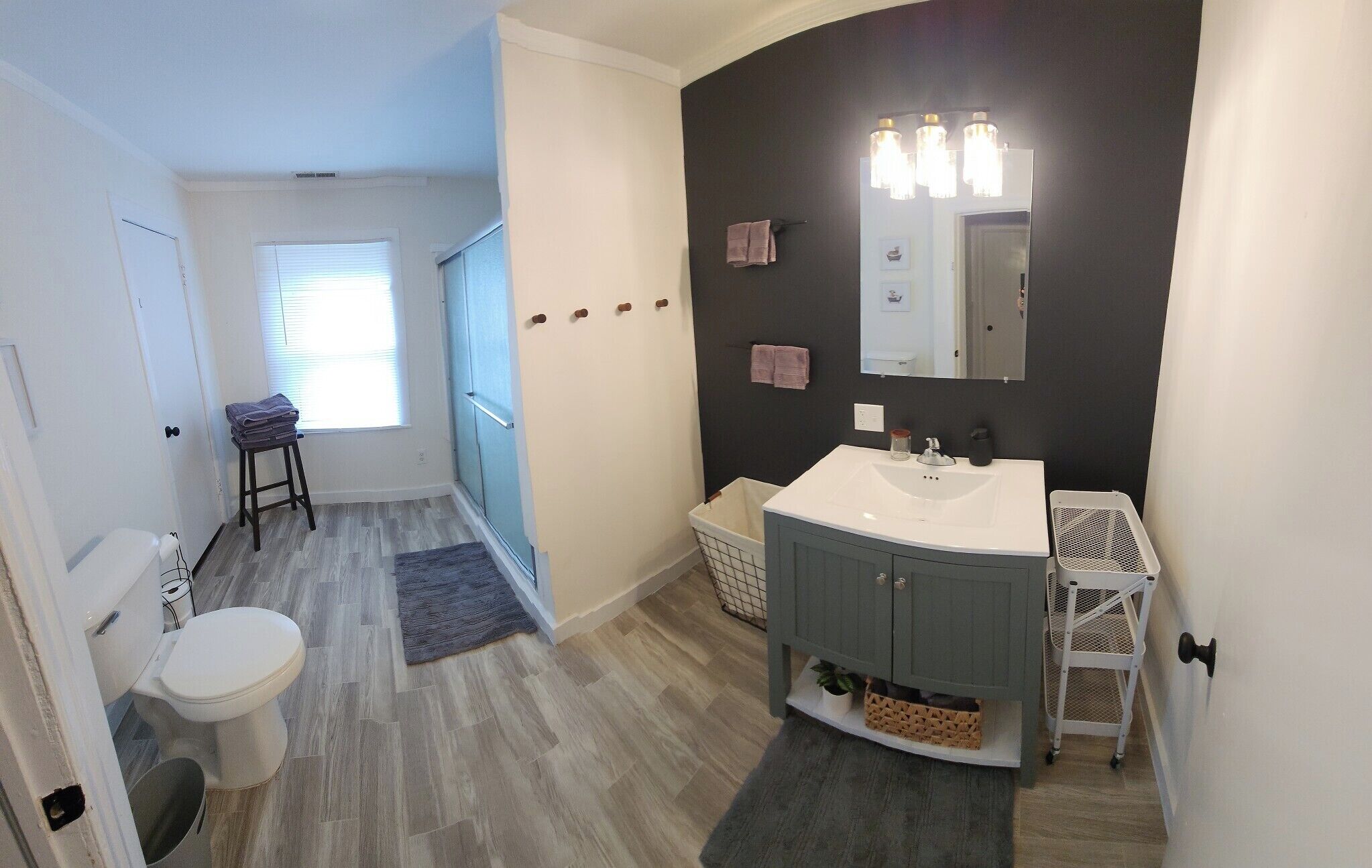 A bathroom with a white sink, dark cabinets, a mirror, and a shower area.
